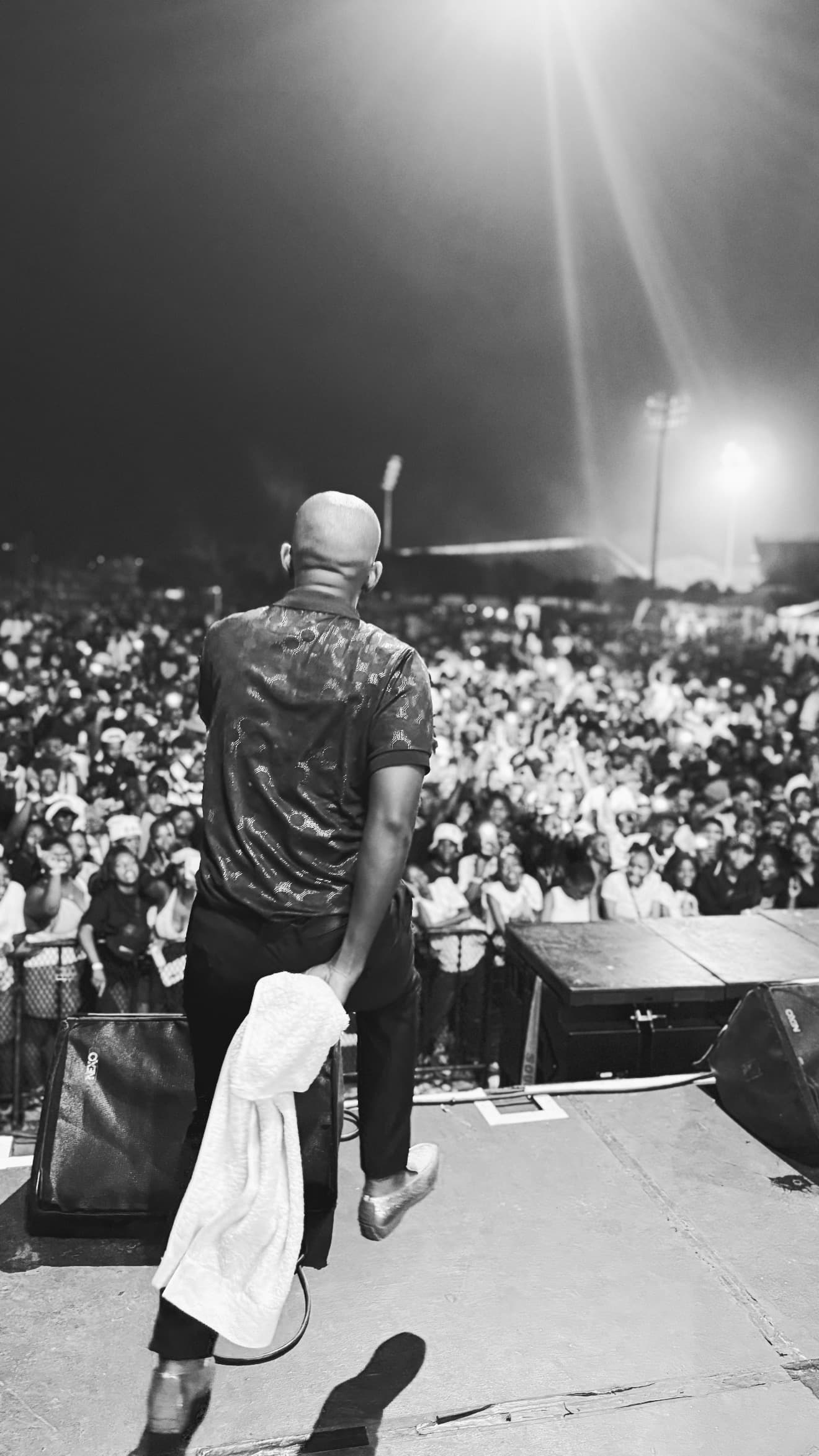 Performer on stage facing a packed festival crowd at night